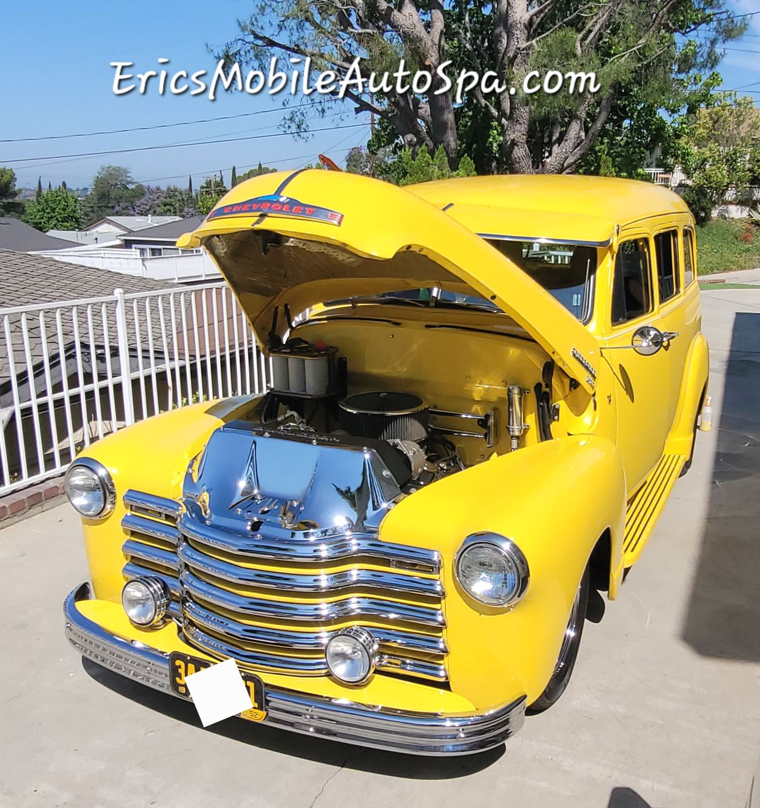 Classic yellow Chevrolet detailed by Eric's Mobile Auto Spa with the hood up in a driveway